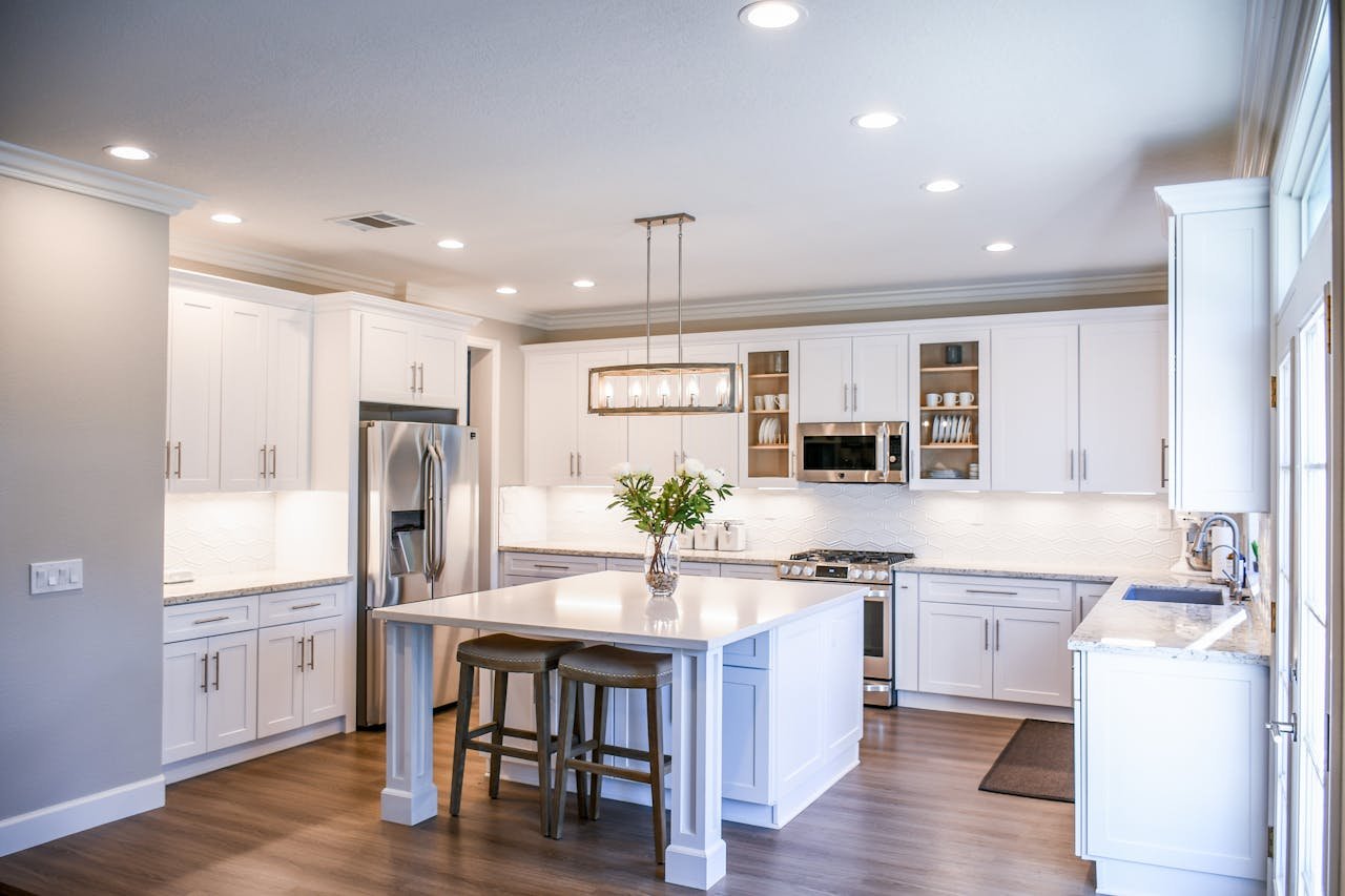 our-experience Elegant white kitchen featuring an island, modern appliances, and ample natural light.